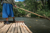 Man using pole to sail the bamboo raft