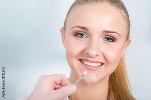 Farbabgleich am Zahn für einen Zahnersatz am Mund einer jungen hübschen Frau