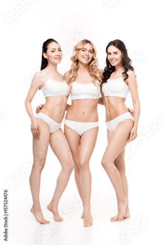 group of smiling women in lingerie standing together isolated on white