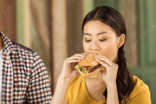 portrait of young asian girl eating tasty burger
