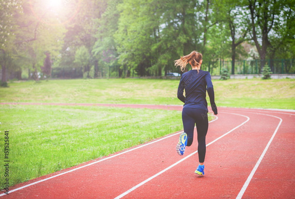 Obraz premium Athletic woman running on track back view, healthy lifestyle