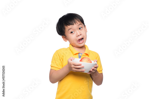 Happy Asian boy holding red apple in bowl.