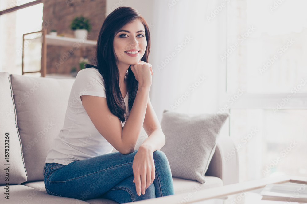 Successful smiling cute teen is sitting on cozy couch in room. She is wearing casual comfortable clothes Successful smiling cute teen is sitting on cozy couch in room. She is wearing casual comfortable clothes