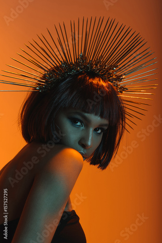 young fashionable african american girl in headpiece with needles looking at camera