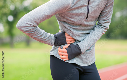 Woman on running track has side cramps during workout photo