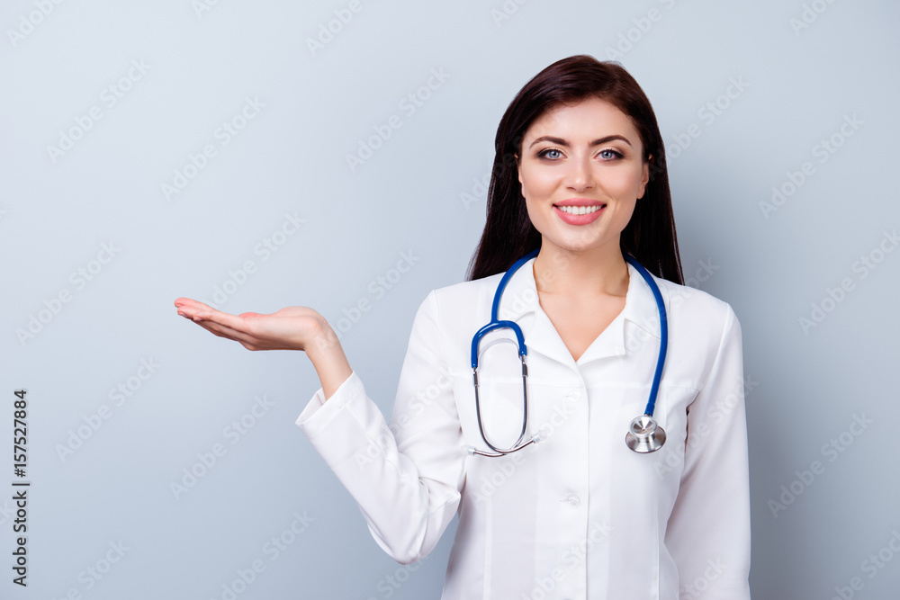 Cute pretty doctor demonstrating product on her hand against gay background Cute pretty doctor demonstrating product on her hand against gay background