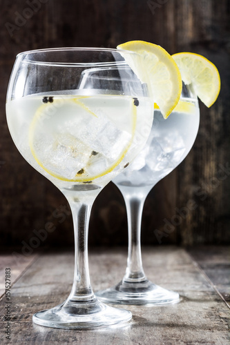 Glass of gin tonic with lemon on wooden background 