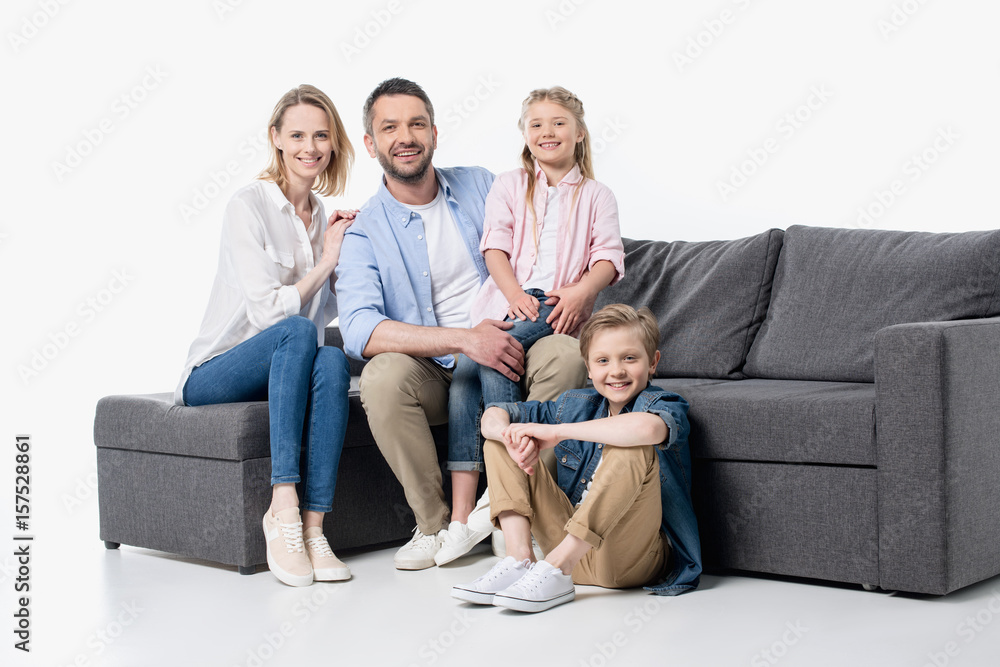 Happy young family with two children sitting together on couch isolated on white Happy young family with two children sitting together on couch isolated on white