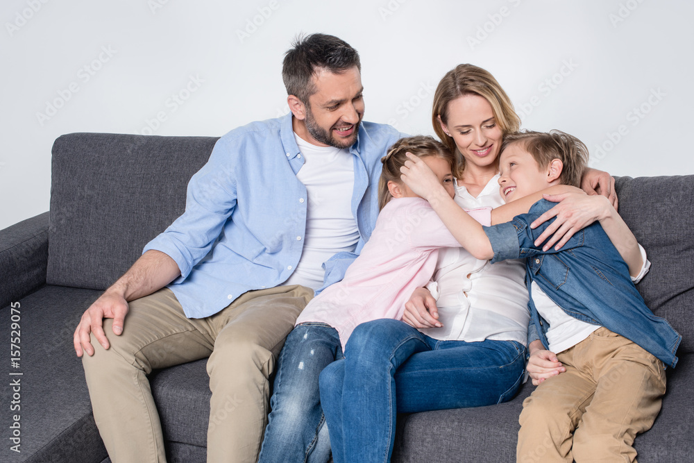Happy family with two children sitting together on sofa and hugging