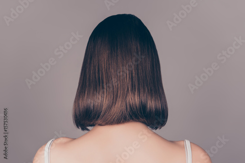 Back view of young beautiful wonam with short symmetric hair isolated on gray background