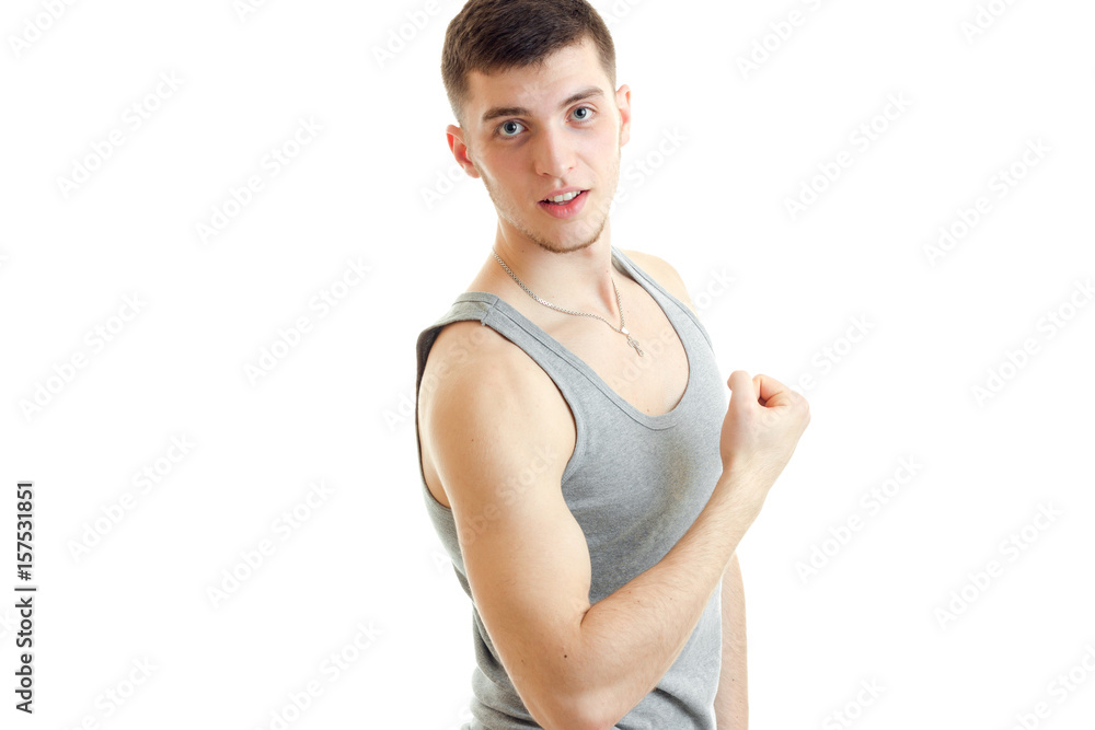 young sporty guy stands sideways and straining the muscle on hand young sporty guy stands sideways and straining the muscle on hand
