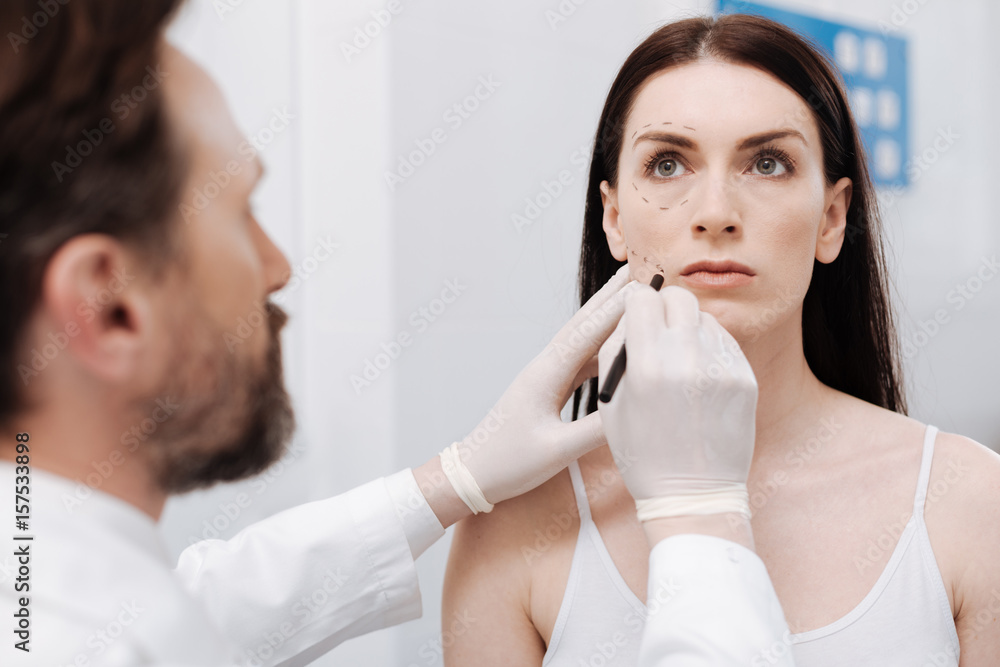 Determined precise doctor using pencil for applying contours