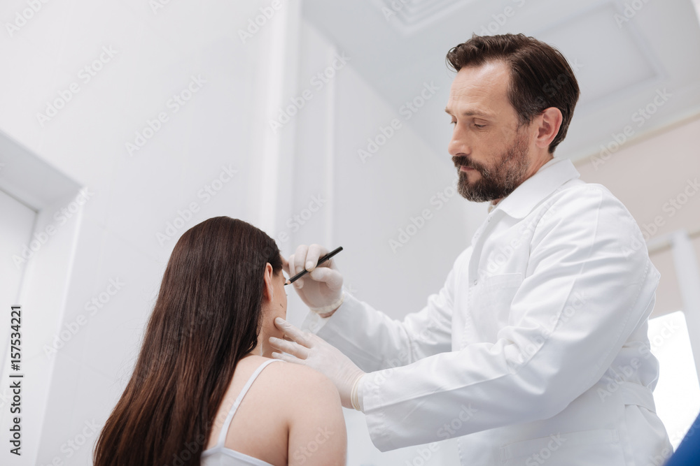 Obraz premium Tender admirable beautician using pencil for marking important areas