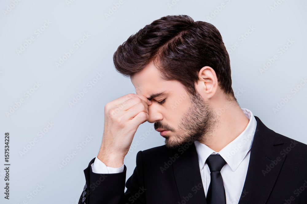 Side view portrait of sad man in formal clothes touching his nose bridge because of having headache Side view portrait of sad man in formal clothes touching his nose bridge because of having headache