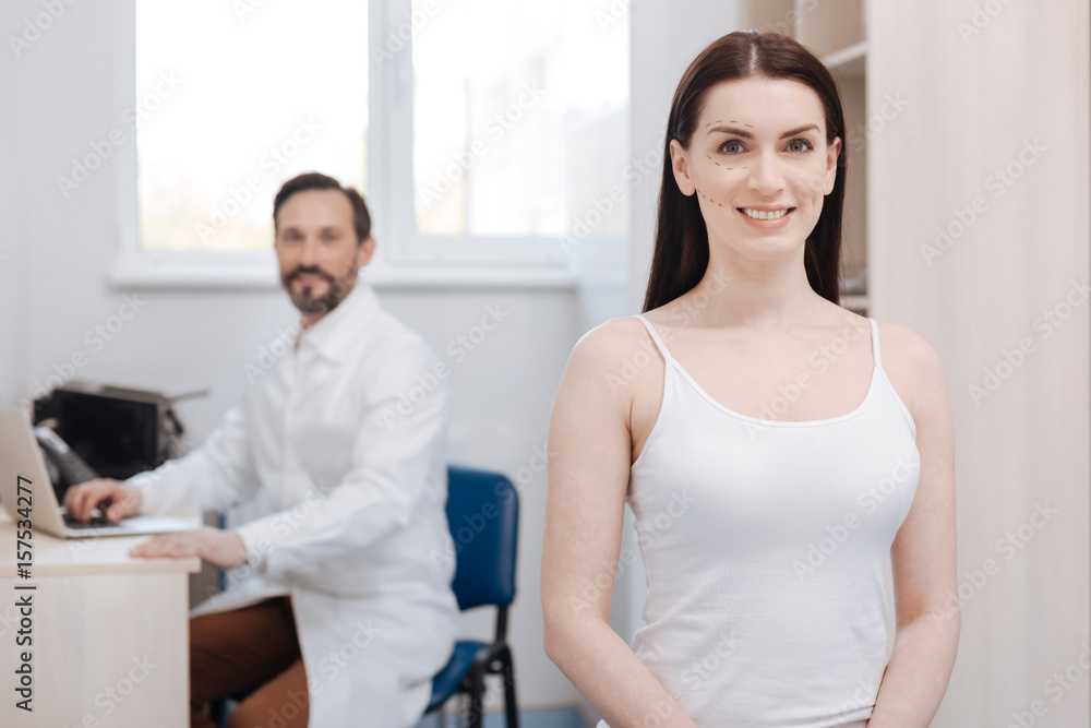 Enthusiastic graceful woman visiting plastic surgeon for lifting procedure Enthusiastic graceful woman visiting plastic surgeon for lifting procedure