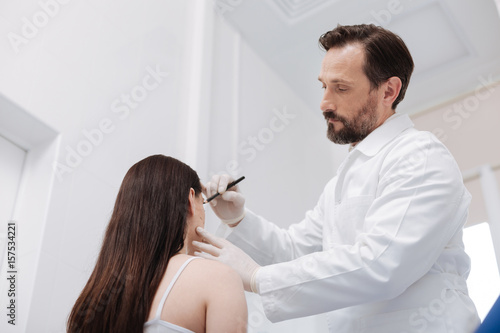 Tender admirable beautician using pencil for marking important areas