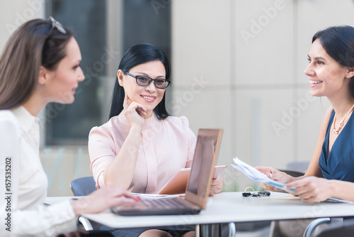Thoughtful woman telling with smiling associates