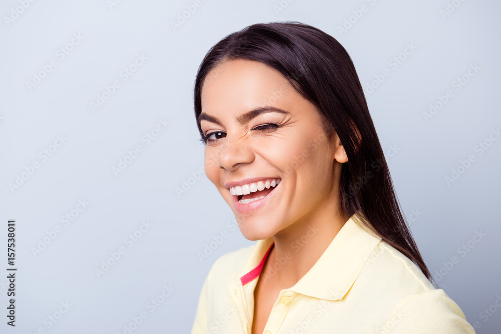 Successful smiling latino girl is winking on light blue background. She has a beaming smile! Successful smiling latino girl is winking on light blue background. She has a beaming smile!