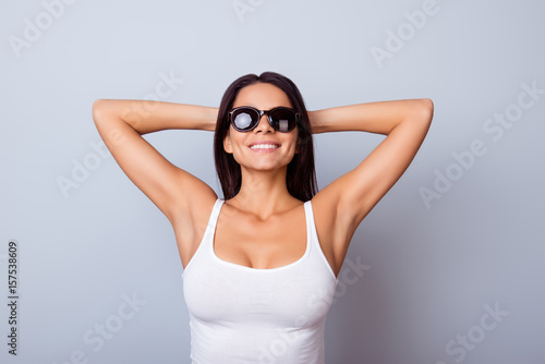 Portrait of a young hispanic girl in casual clothes and sunglasses, standing on the blue background