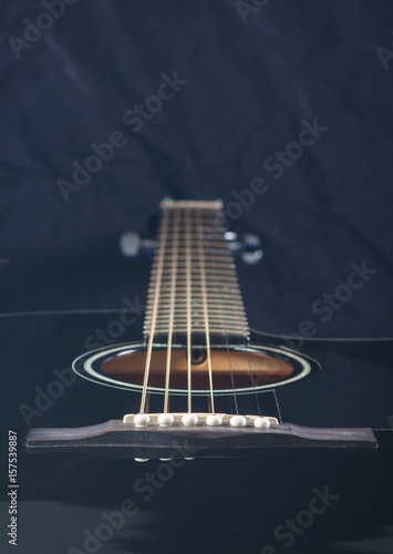 Black acoustic guitar on a black background