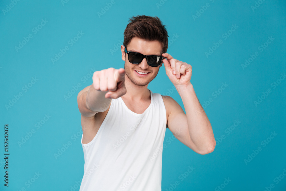 Cheerful guy in sunglasses and singlet pointing finger at camera Cheerful guy in sunglasses and singlet pointing finger at camera