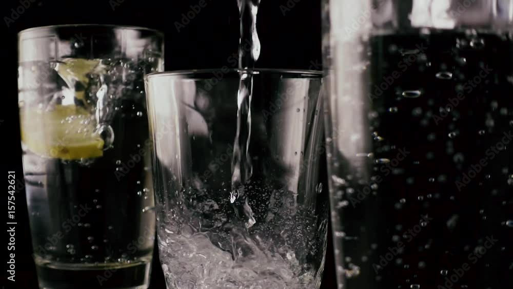 Slow motion. In two glasses with soda fall ice and lemon, in the third pour water Slow motion. In two glasses with soda fall ice and lemon, in the third pour water