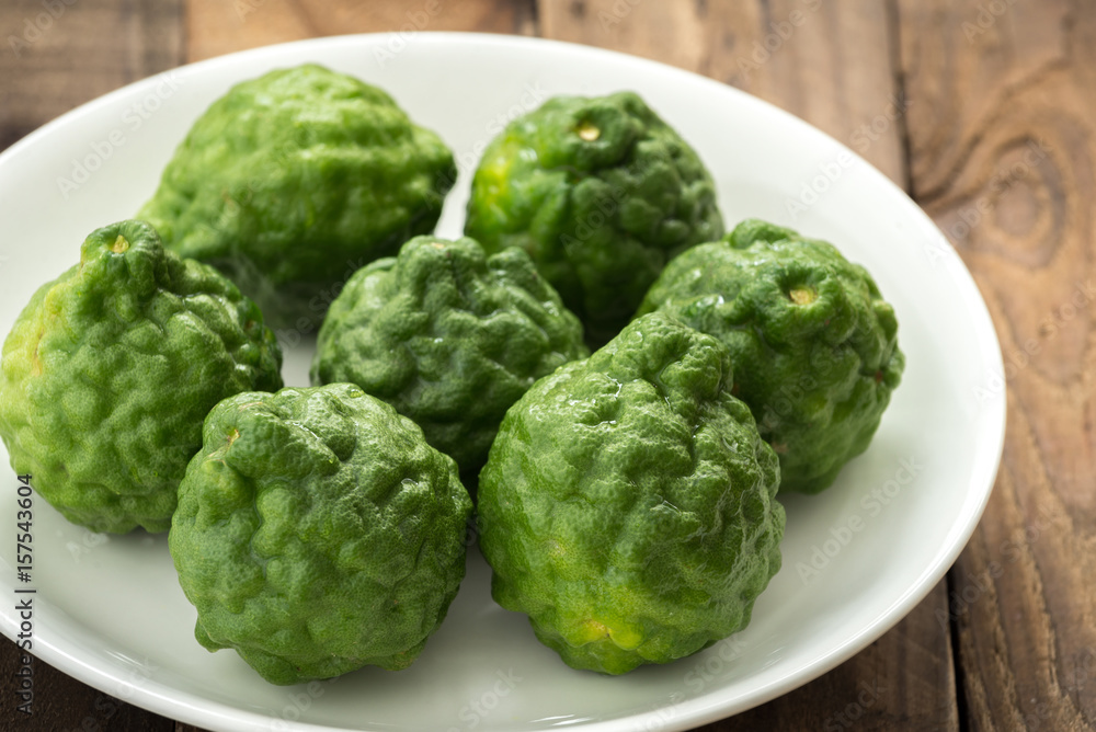 Obraz premium Kaffir lime or lime with white plate on wood