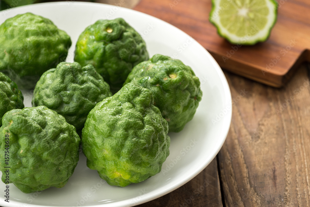Kaffir lime or lime with white plate on wood
Kaffir lime or lime with white plate on wood