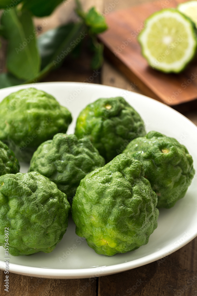 Kaffir lime or lime with white plate on wood
Kaffir lime or lime with white plate on wood