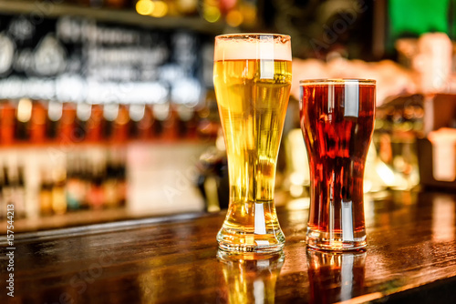 Glass of light and dark beer on a pub with bokeh background