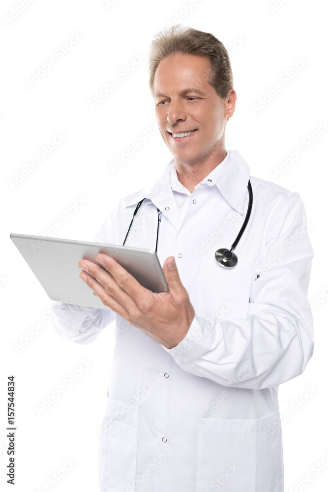 smiling middle aged doctor in white coat using digital tablet isolated on white smiling middle aged doctor in white coat using digital tablet isolated on white