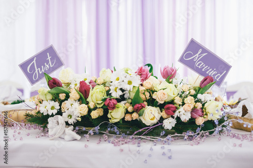 Violet cards with letering 'Just married' pinned in the bouquet of yellow roses photo