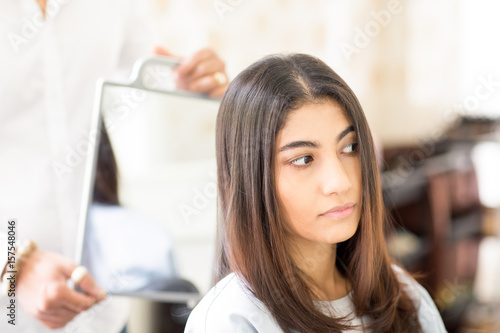 Canvas Print Serious woman looking at her haircut in hair salon