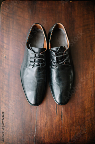 Black leather shoes stand on wooden floor