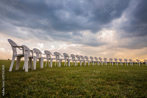 White plastic chairs on a meadow arranged in a circle for meditation