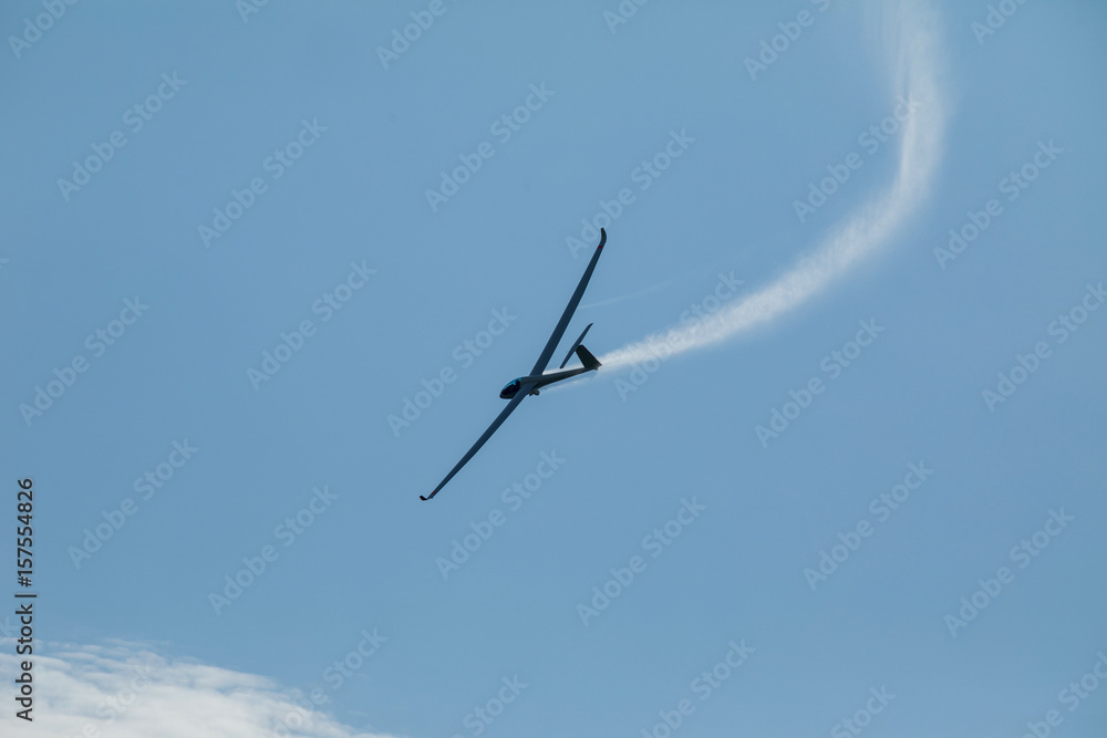 A glider flying in the blue sky ejects the water before the landing. A glider flying in the blue sky ejects the water before the landing.