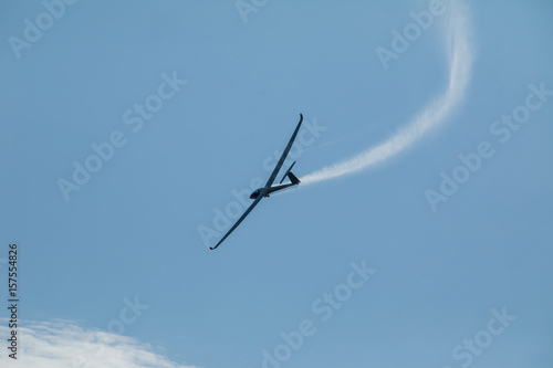A glider flying in the blue sky ejects the water before the landing.