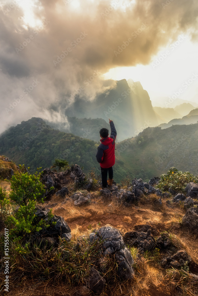 bbeautiful landscape.Men wear red shirt stand looking mountain and fog valley,Mountain layer in morning sun light. at Chiangdao mountain,Chiangmai Thailand bbeautiful landscape.Men wear red shirt stand looking mountain and fog valley,Mountain layer in morning sun light. at Chiangdao mountain,Chiangmai Thailand