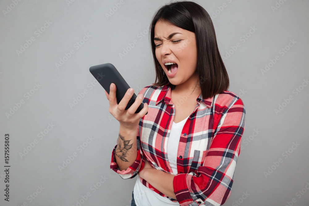 Angry young asian woman isolated using phone. Angry young asian woman isolated using phone.