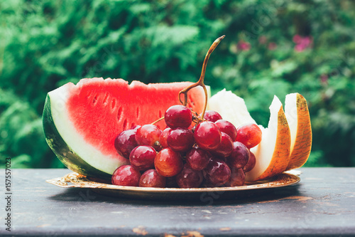 summer fruit berry still life with slices of watermelon, melon and grape bunch on the table photo