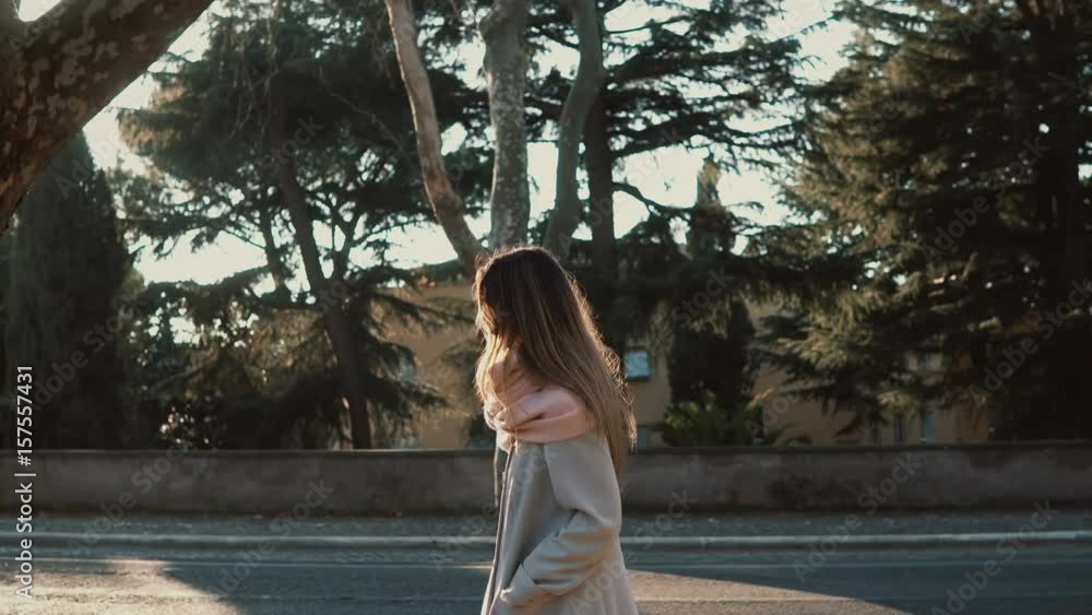 Attractive young woman walking at park near the road at sunset. Female enjoying the bright spring day, explore the city. Attractive young woman walking at park near the road at sunset. Female enjoying the bright spring day, explore the city.