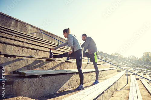 couple stretching leg on stands of stadium