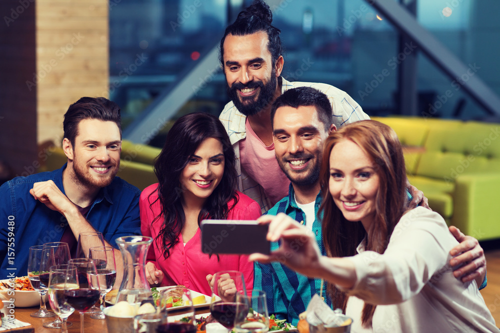 Obraz premium friends taking selfie by smartphone at restaurant