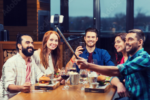 friends taking selfie by smartphone at restaurant