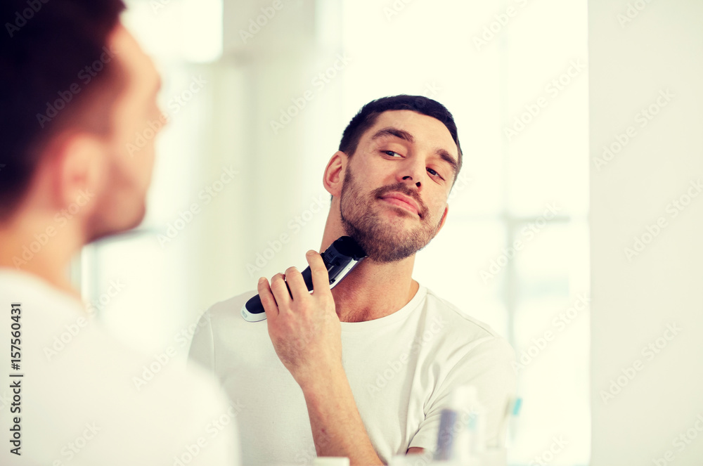 man shaving beard with trimmer at bathroom man shaving beard with trimmer at bathroom