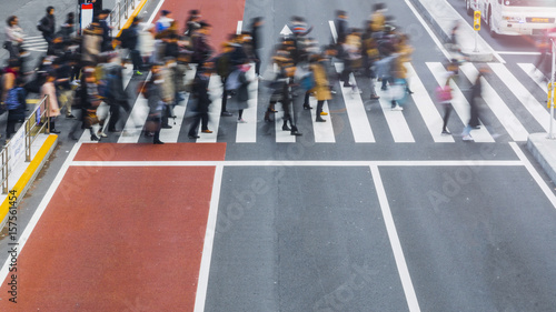 Blur business people are walking across the pedestrian crosswalk in the city road with the signage on arrow on the grey and red concrete road. (on top aerial view) photo