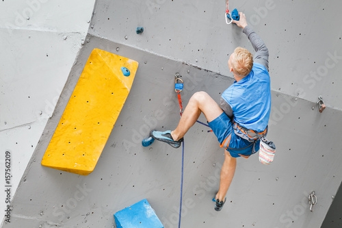 Male Climber sportsman hanging on artificial Climbing Wall, Competition in difficulty contest