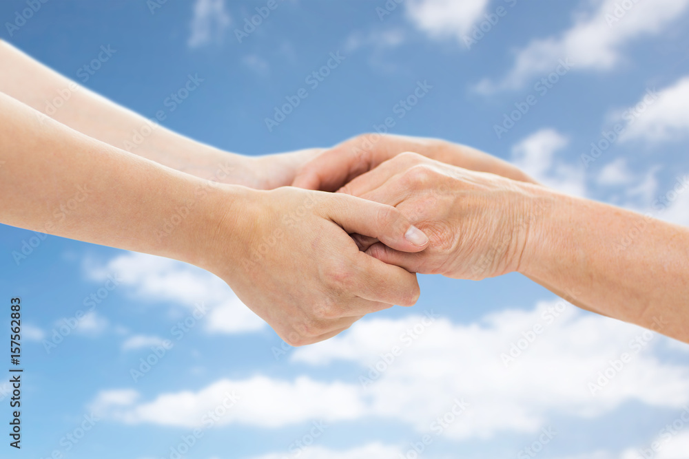 close up of senior and young woman holding hands close up of senior and young woman holding hands