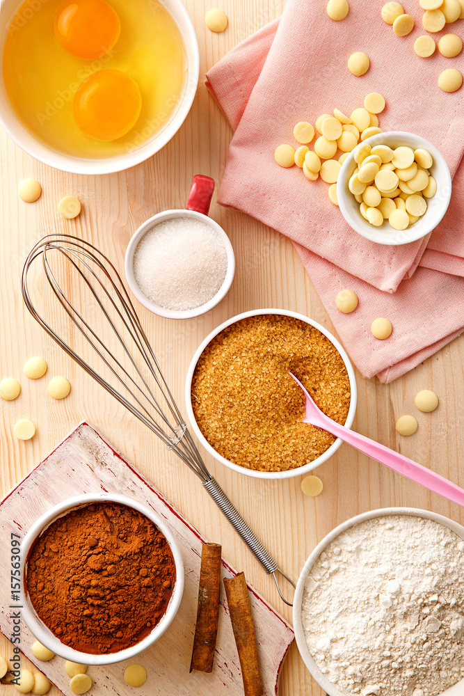 Baking utensils and ingredients. Egg yolk, cocoa, sugar, flour, whisker, spoons, cinnamon, bowl, sweet decoration elements. Top view. Flat lay Baking utensils and ingredients. Egg yolk, cocoa, sugar, flour, whisker, spoons, cinnamon, bowl, sweet decoration elements. Top view. Flat lay