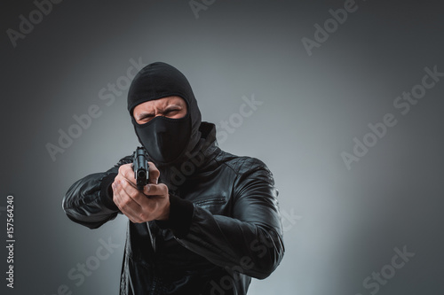 Obraz na plátně Robber with a gun, studio shot